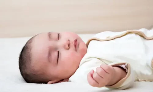 Un bébé dort allongé sur le dos